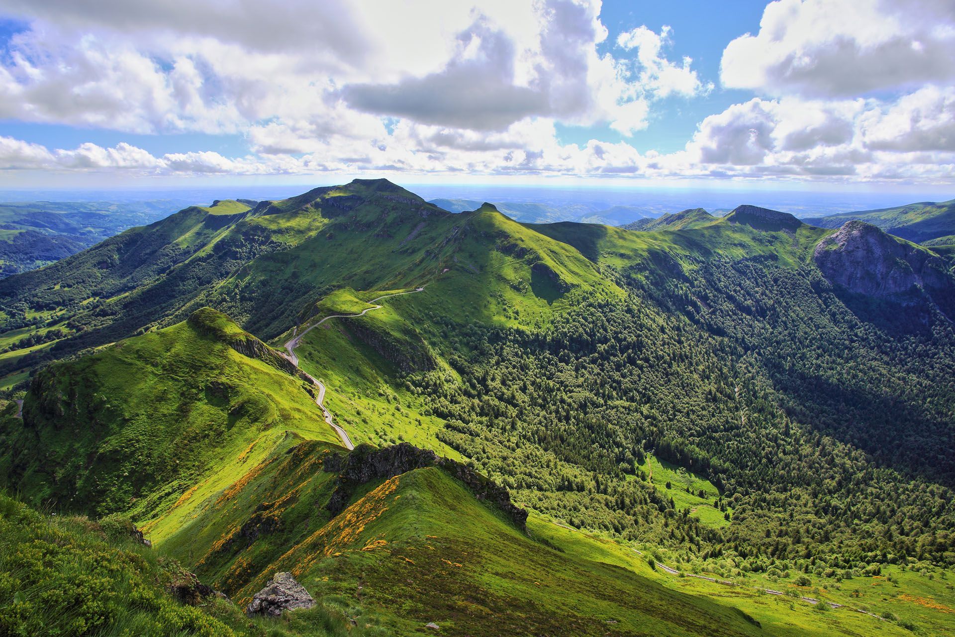 Green mountains under a blue sky with white clouds.
