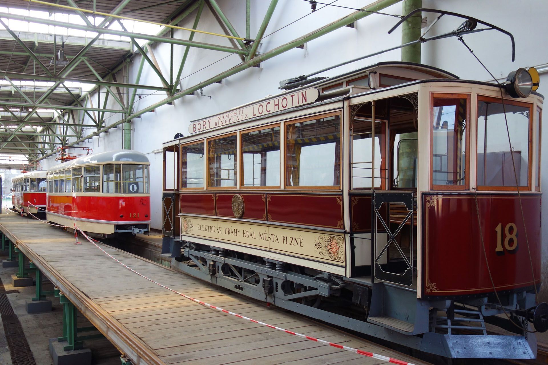 Vintage maroon tram with number 18 on display, alongside others in a depot.