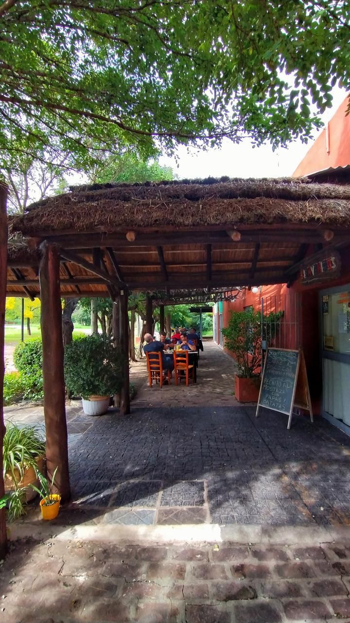 Una zona de estar al aire libre a la sombra para un restaurante, con techo de paja, suelo de ladrillo y mesas