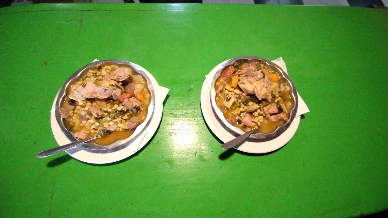 Dos cuencos de abundante estofado de carne y verduras en platos blancos, colocados sobre una mesa de color verde brillante.