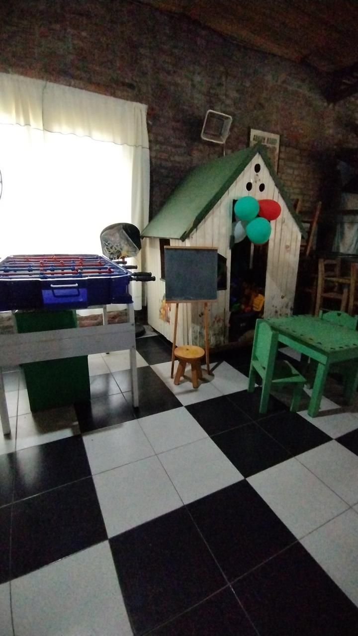 Un área de juegos infantiles con una casita de madera, una pizarra, un futbolín 