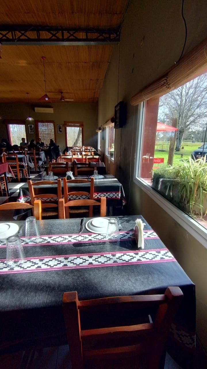 Un comedor con mesas de madera cubiertas con manteles estampados, sillas de madera 