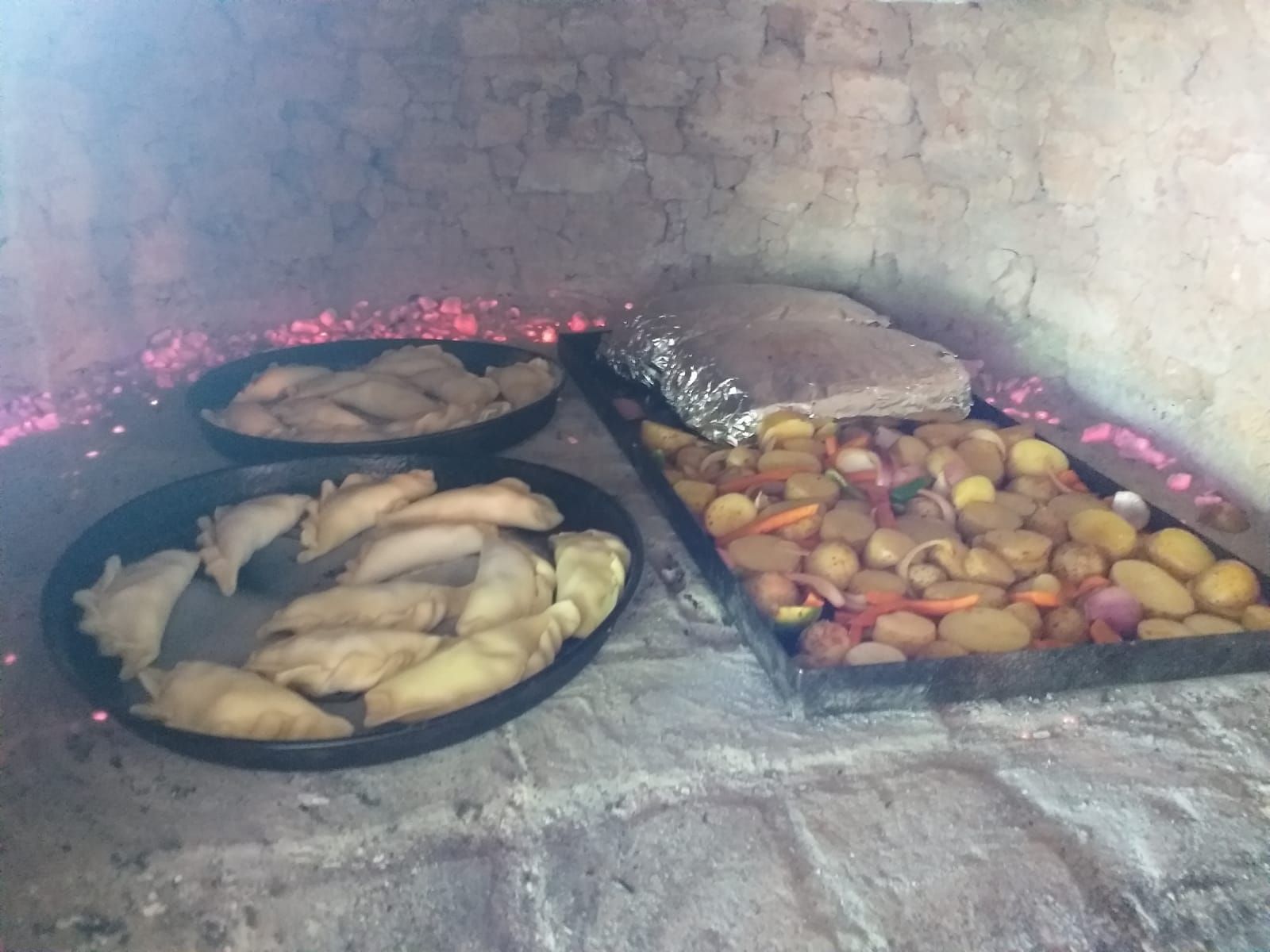 Dos bandejas circulares de empanadas y una bandeja rectangular de patatas y verduras 
