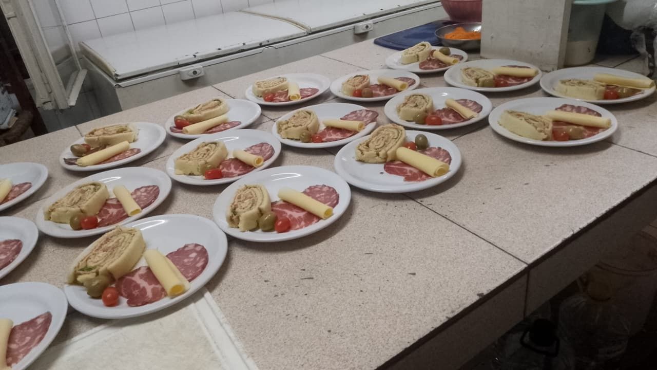 Numerosos platitos blancos dispuestos sobre un mostrador, cada uno con una loncha de rollo de carne