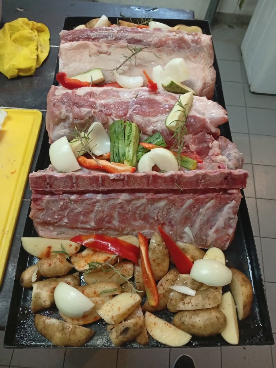 Costillas de cerdo crudas y trozos de patatas, cebollas y pimientos morrones 