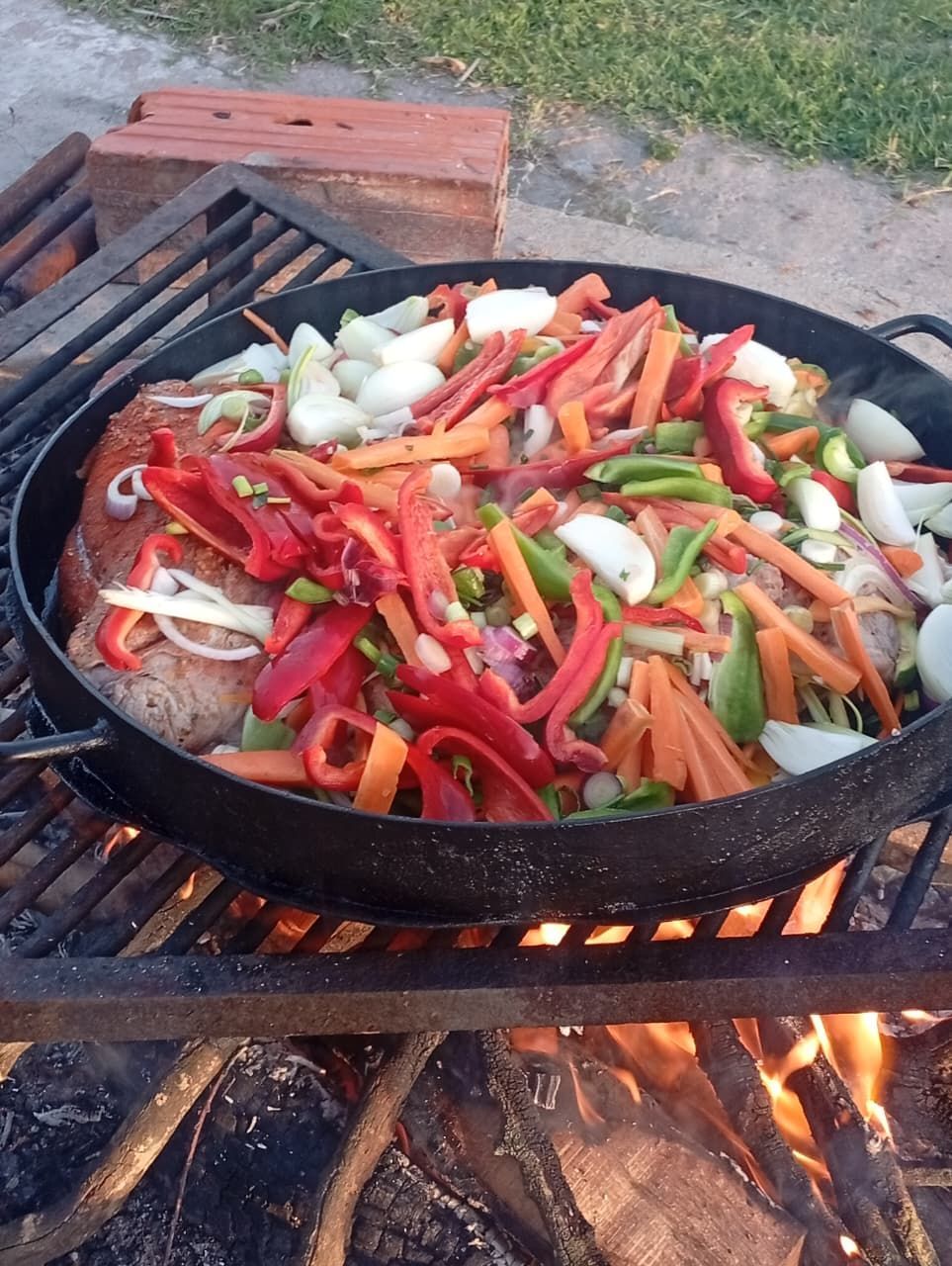 Una sartén grande con pimientos rojos en rodajas, cebollas, zanahorias y carne 