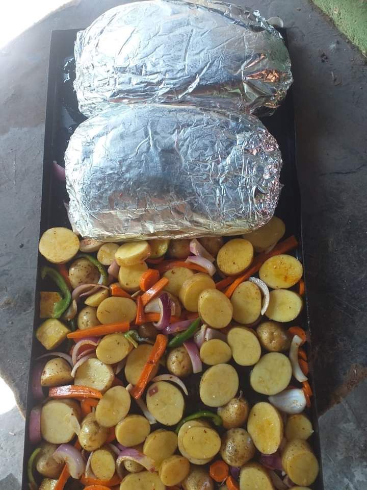 Una bandeja rectangular para hornear llena de patatas, zanahorias y cebollas en rodajas