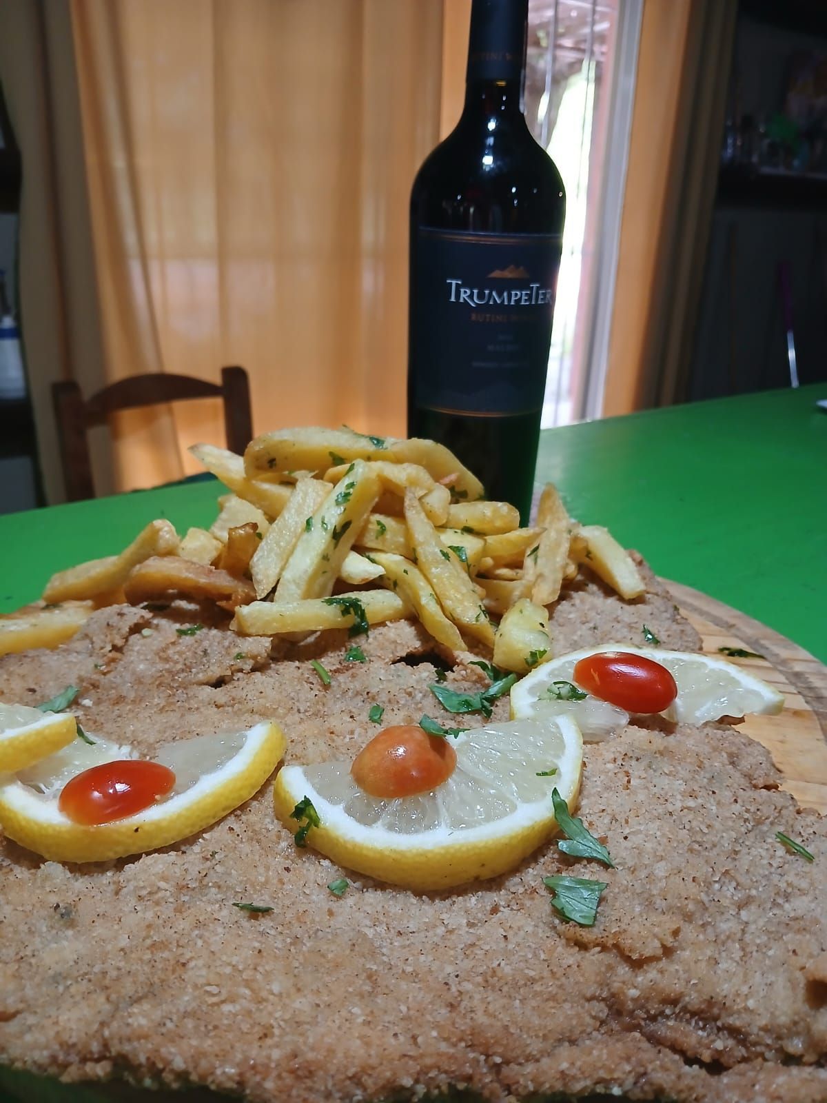 Una chuleta grande empanada, cubierta con rodajas de limón y tomates cherry