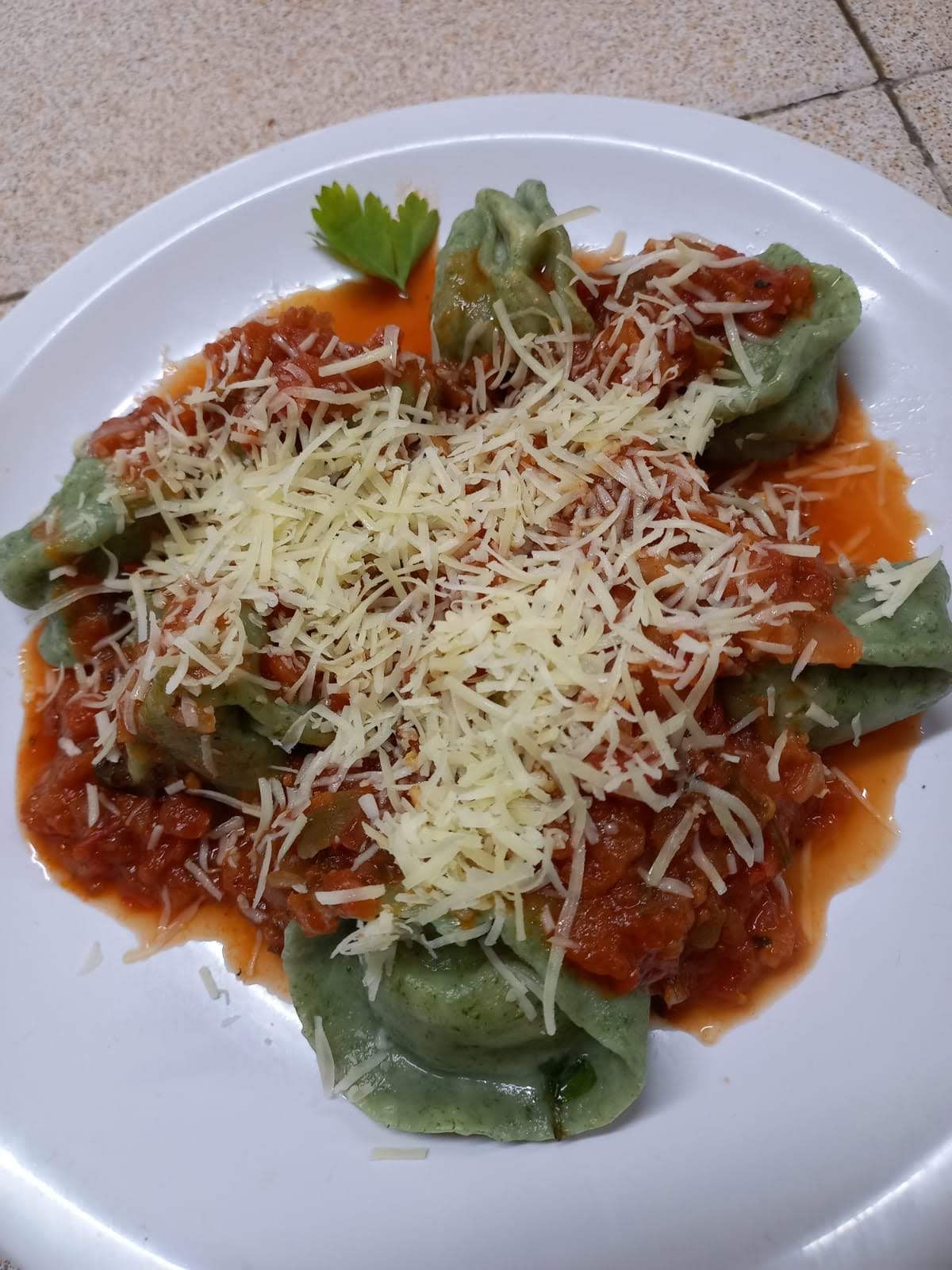 Un plato de pasta con espinacas, cubierta con una salsa espesa de carne roja