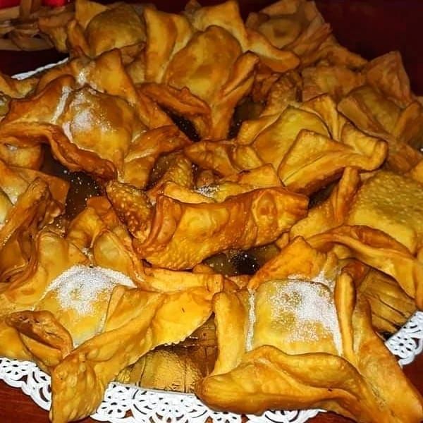 Una bandeja repleta de pastelitos cuadrados fritos, de color marrón dorado