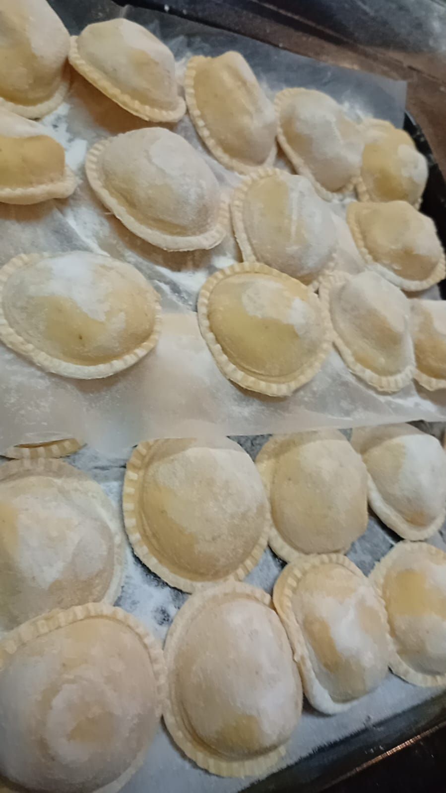 Una bandeja de empanadillas redondas, recién preparadas y con los bordes ondulados