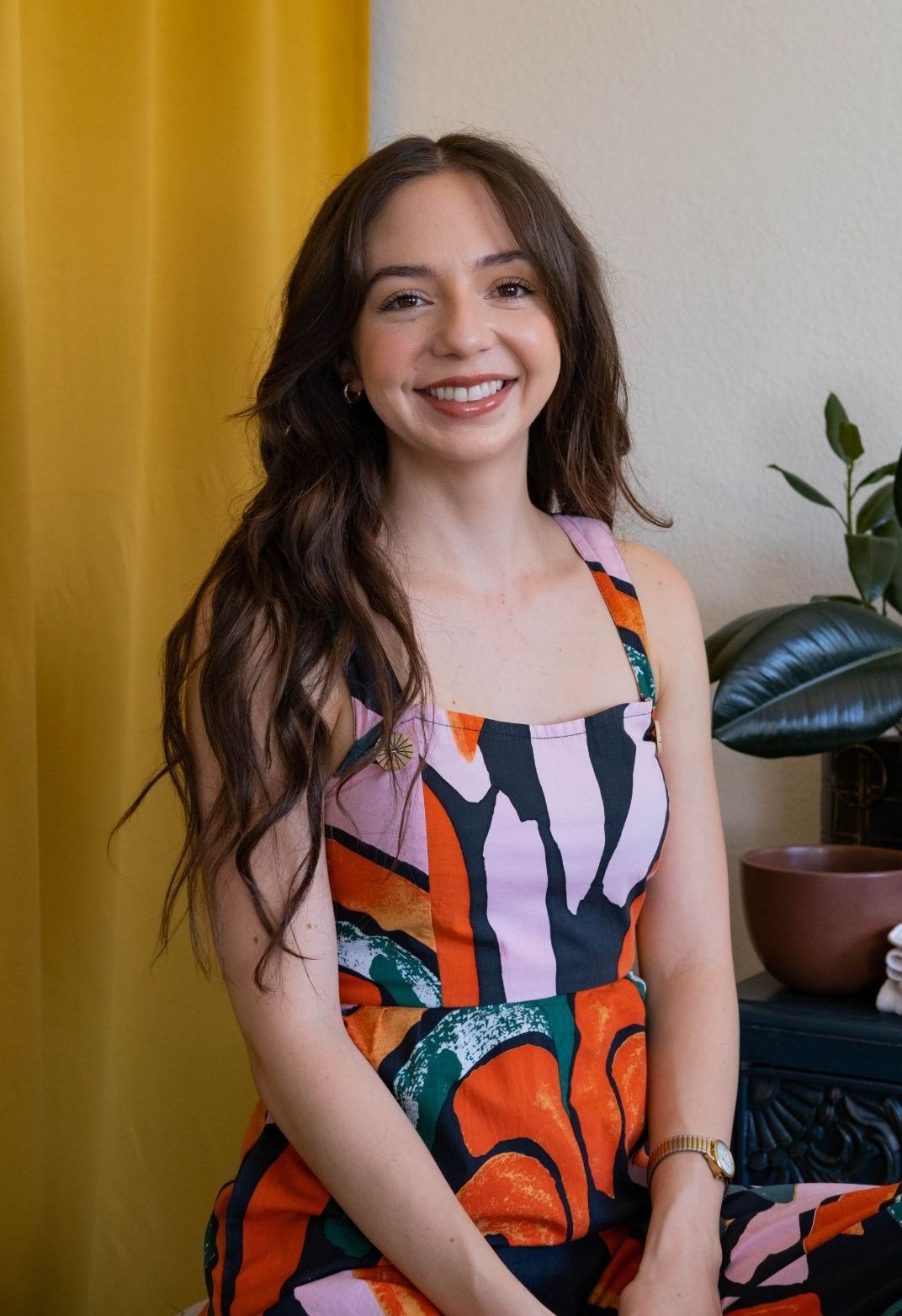 a portrait of Briana, Esthetician wearing abstract floral print jumpsuit