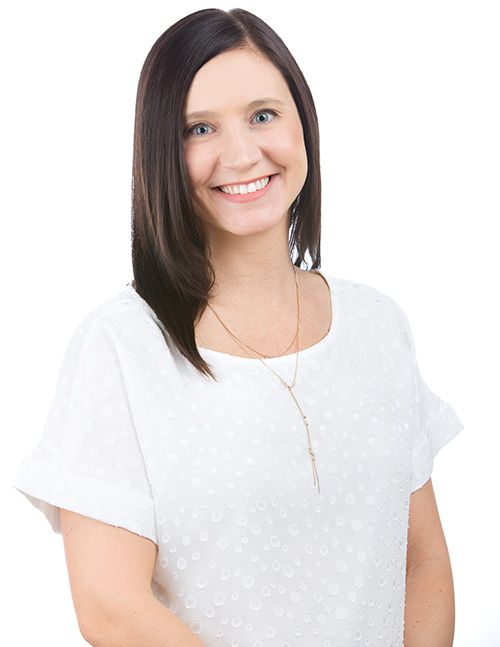 a portrait of Dr. Katie Osley, Board-Certified Dermatologist wearing a white blouse and gold long necklace