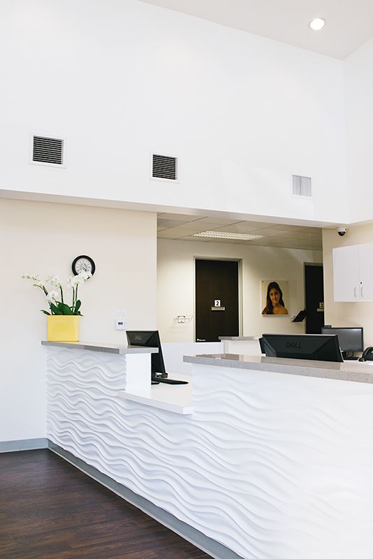 a white reception desk in a dental office with a vase of flowers on it