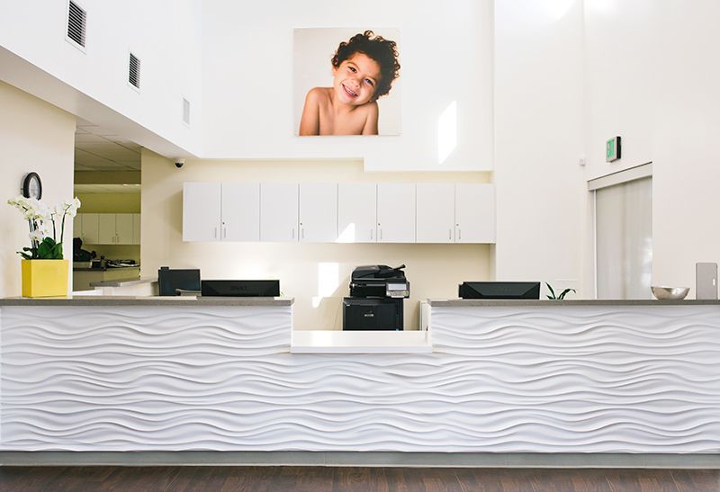 a reception desk in a hospital with a picture of a child on the wall above it
