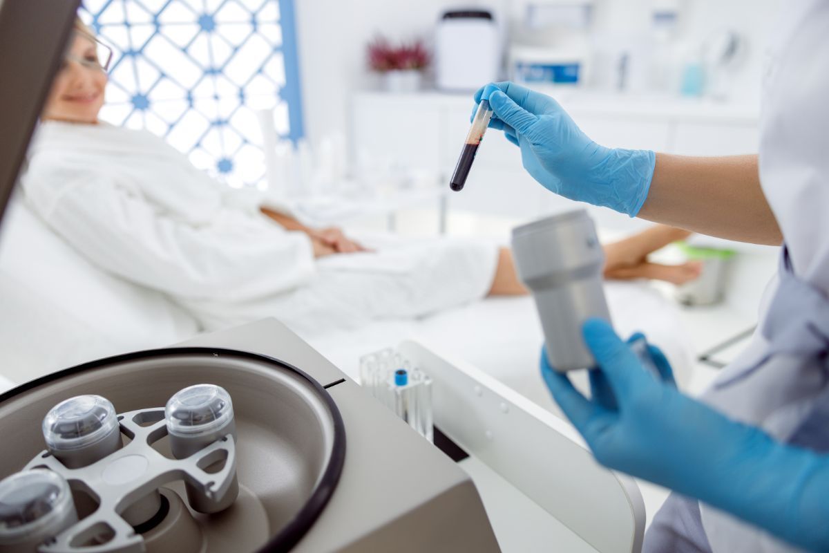 a nurse is holding a test tube in front of a centrifuge