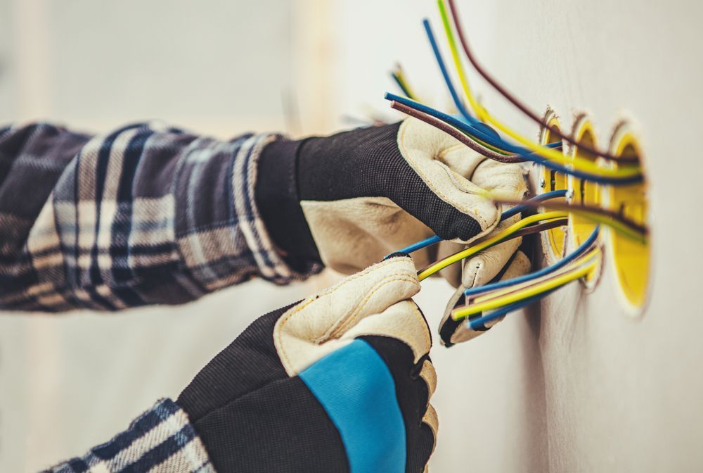 Hands Of An Electrician With Safety Gloves Connecting Colorful Wires — Stanayr Electrical in Gulliver, QLD