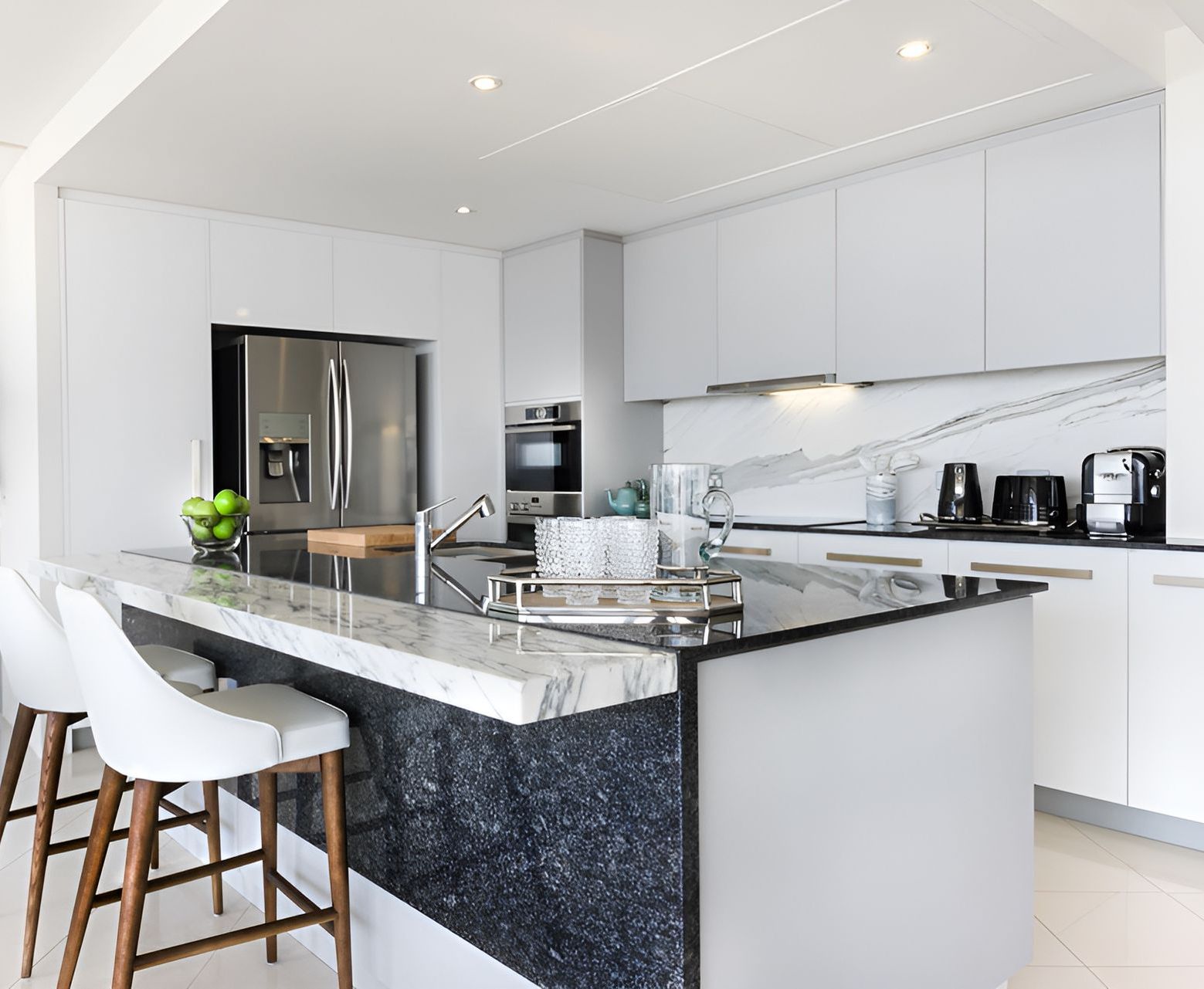 A kitchen with white cabinets , black counter tops , and a large island — Prime Built Group in Bowral, NSW