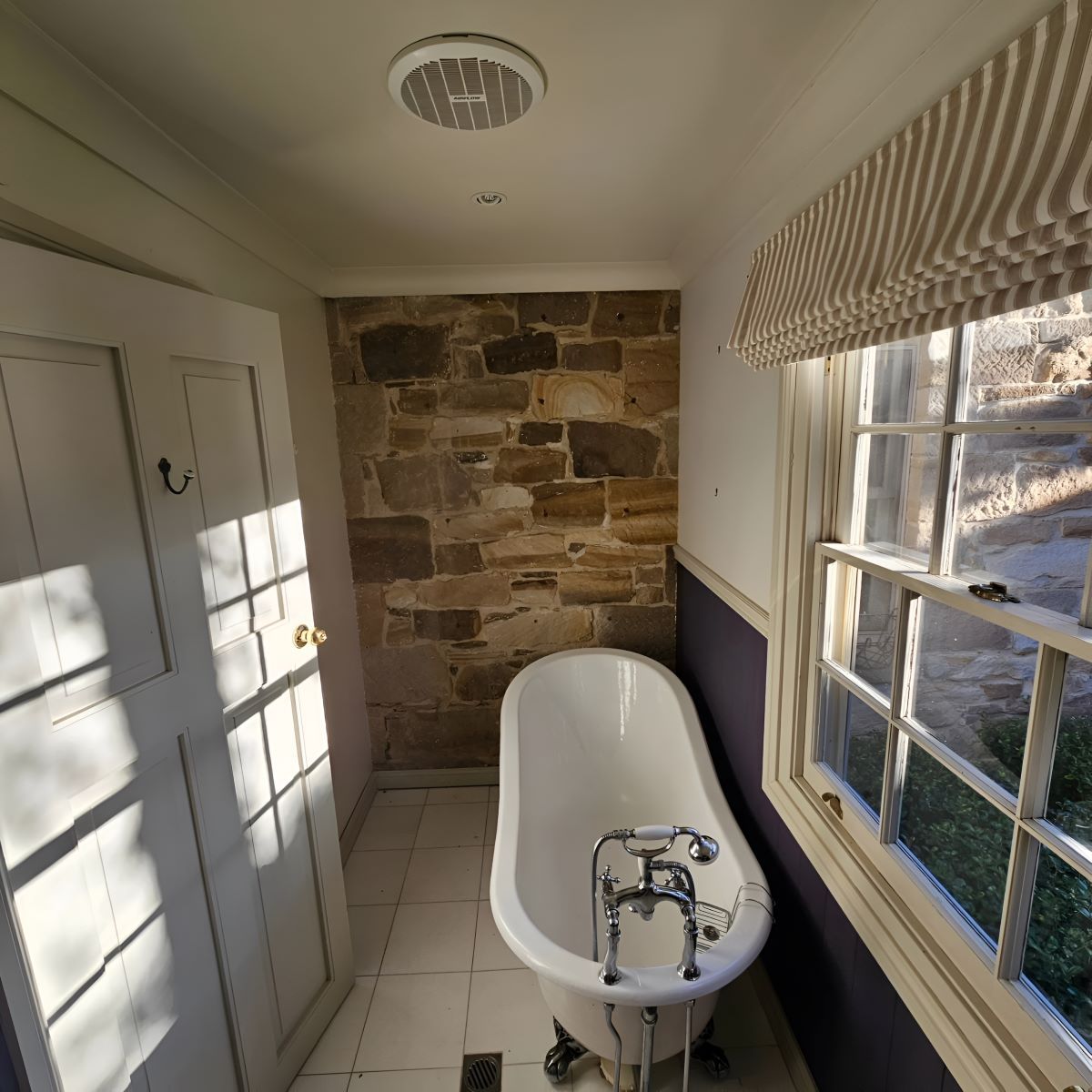 A Bathroom With a Claw Foot Tub and a Stone Wall — Prime Built Group in Bowral, NSW