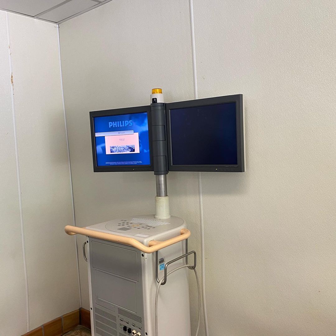 Two monitors are mounted to a wall next to a computer.