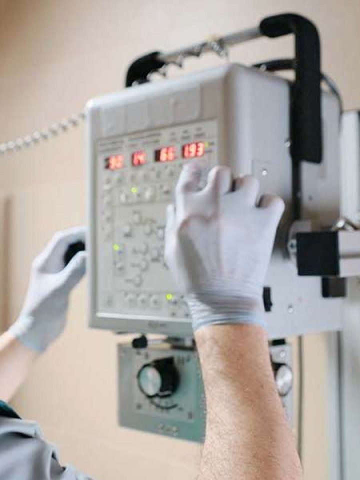A person wearing gloves is using an x-ray machine.