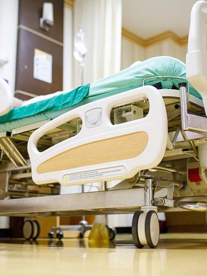 A hospital bed is sitting on the floor in a hospital room.