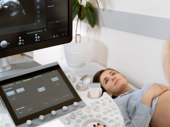 A pregnant woman is laying on a bed getting an ultrasound.