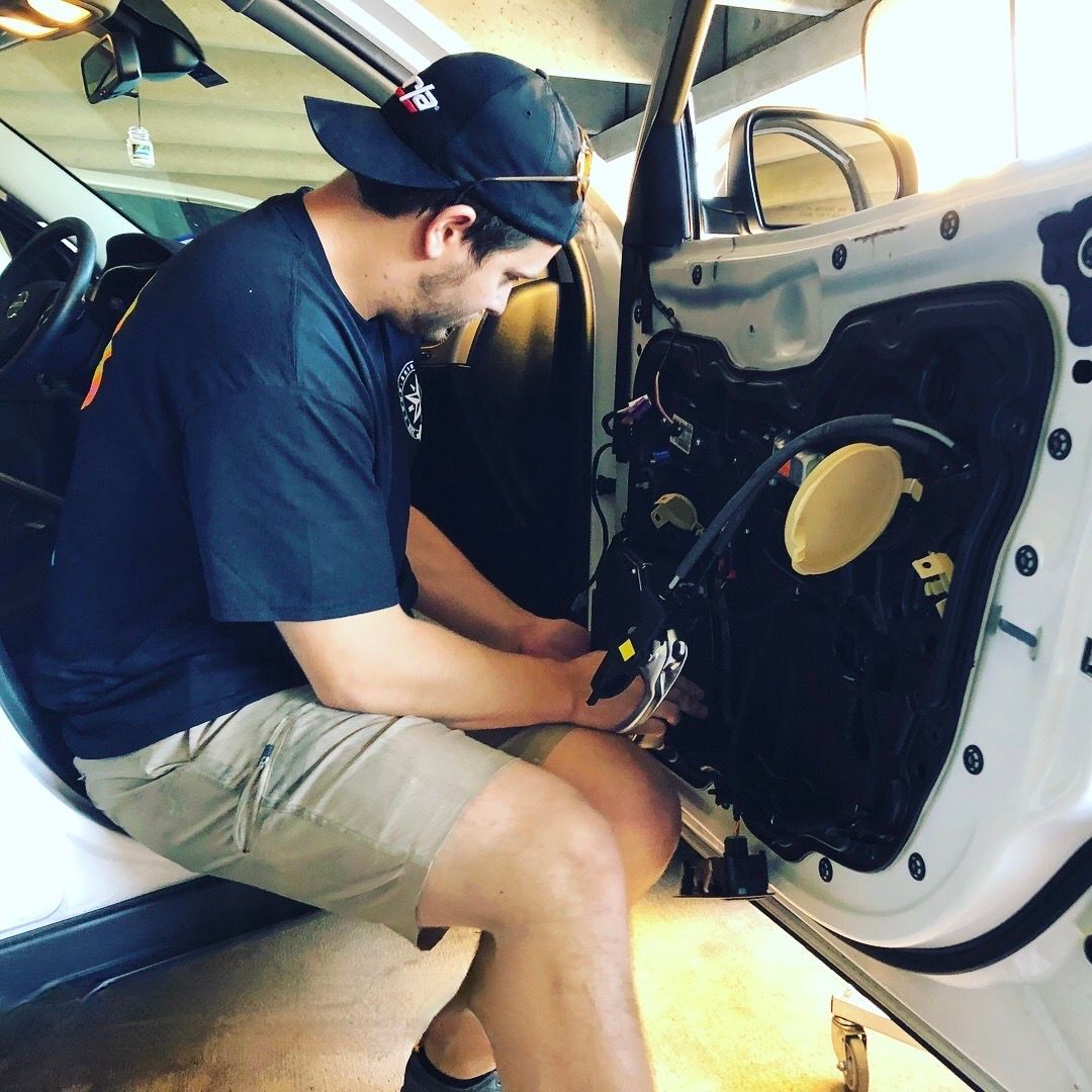 A man in a hat is working on a car door