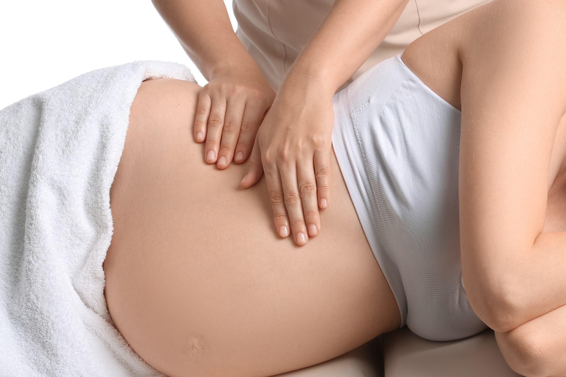 A person receiving a massage, with hands on their abdomen, covered by a white towel, indoors.