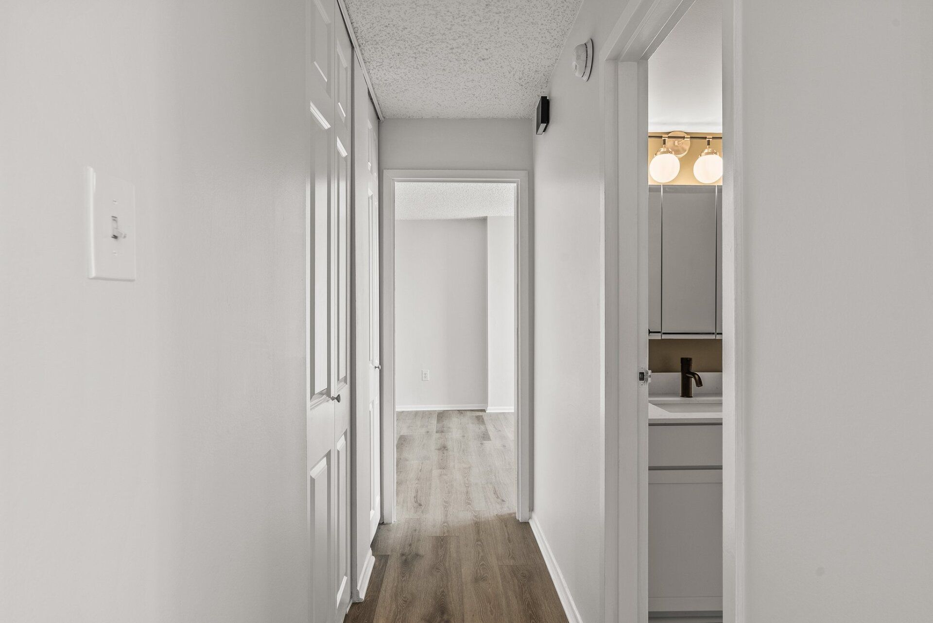 A hallway in a house with a bathroom and a sink.
