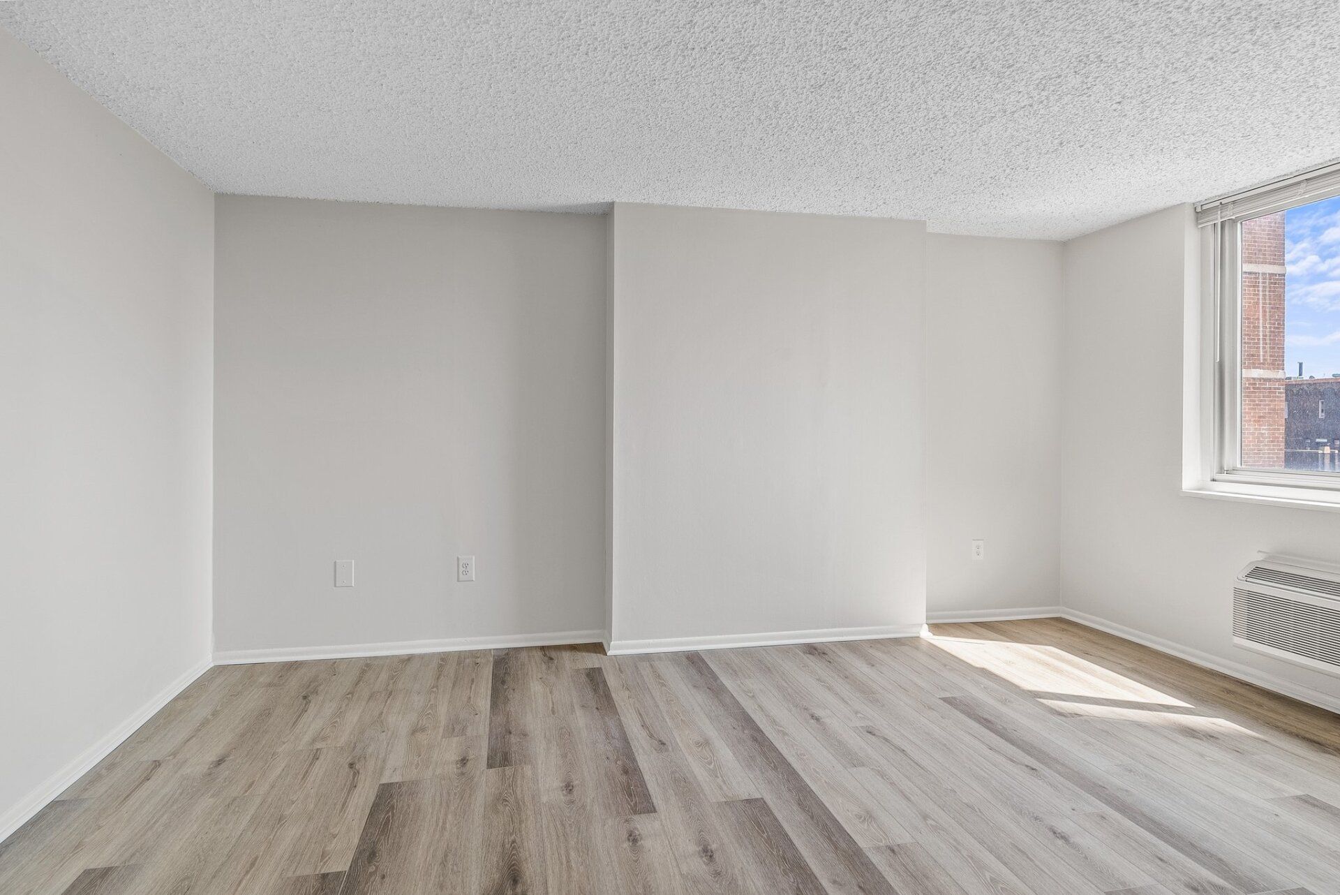 An empty living room with hardwood floors and a window.