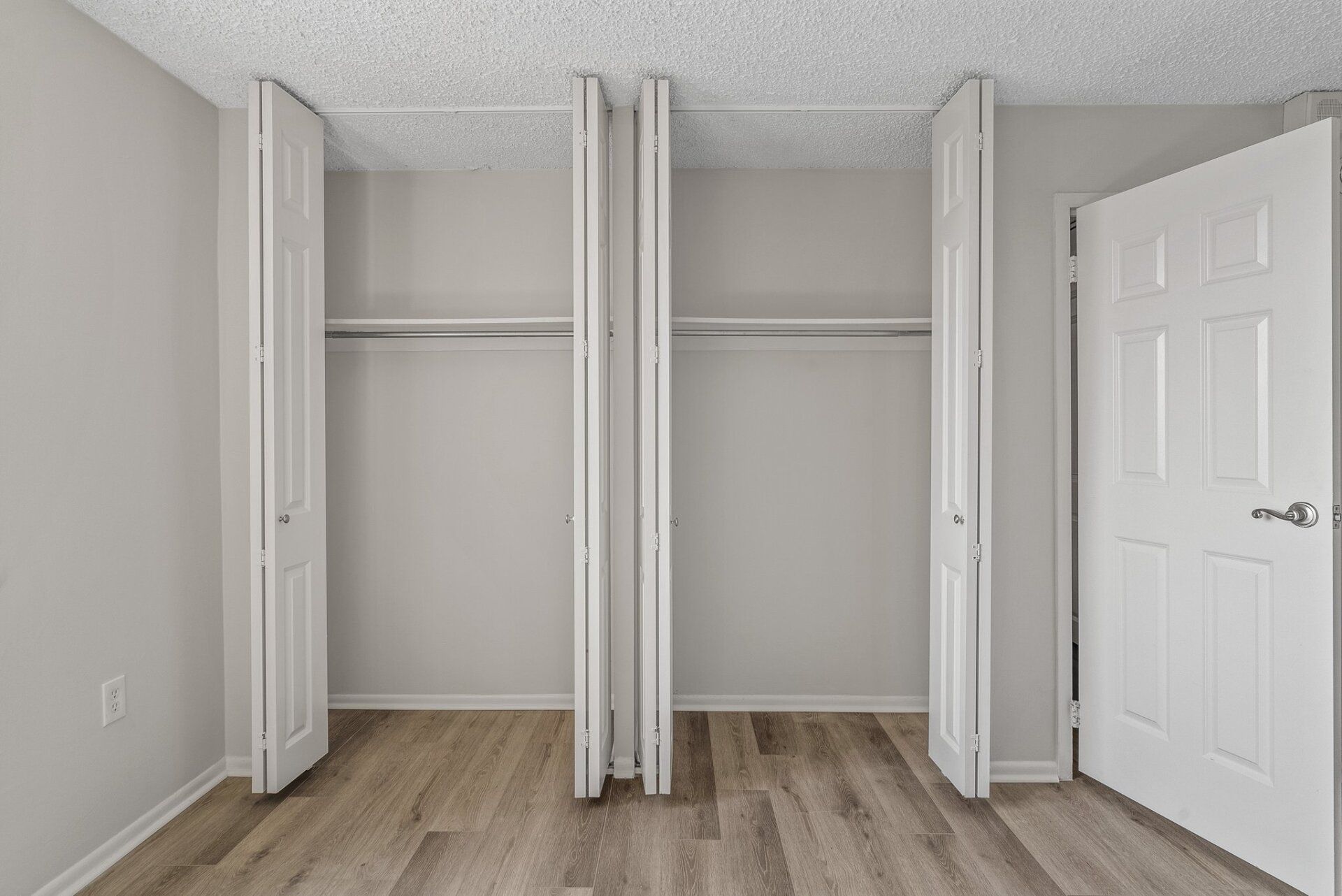 A bedroom with empty closets and a wooden floor.