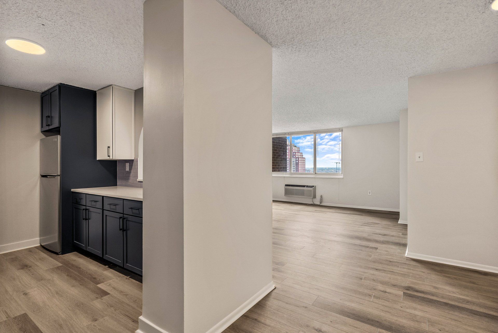 An empty apartment with a kitchen and a living room.