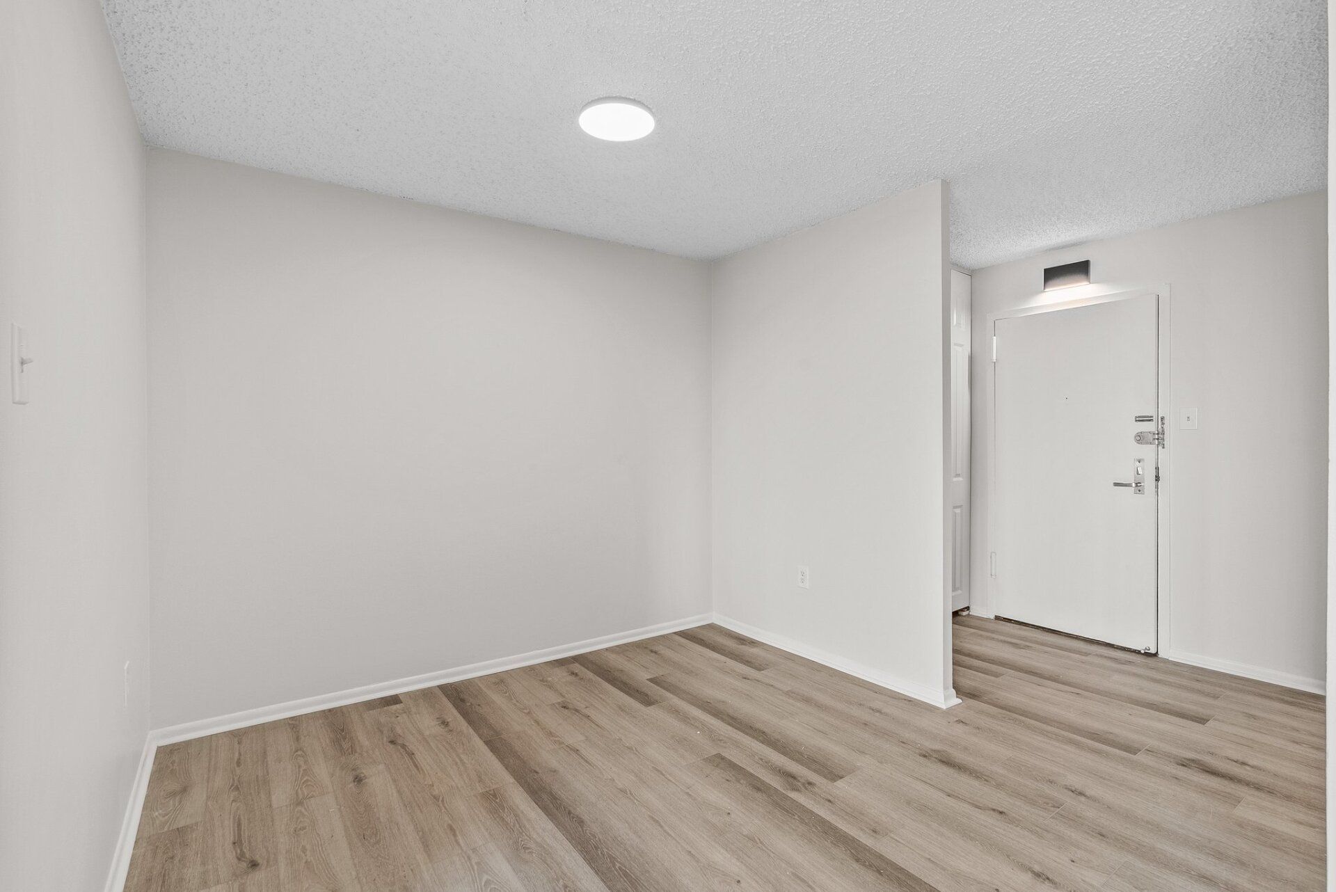 An empty room with hardwood floors and white walls.