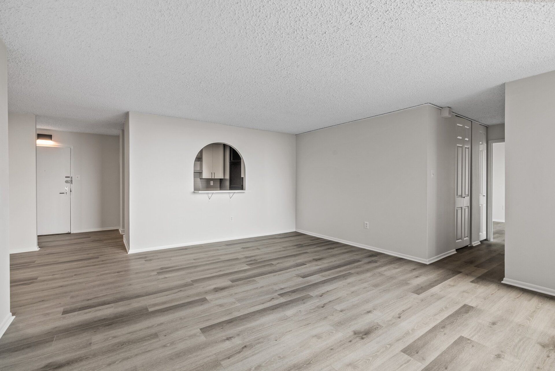 An empty living room with hardwood floors and white walls.