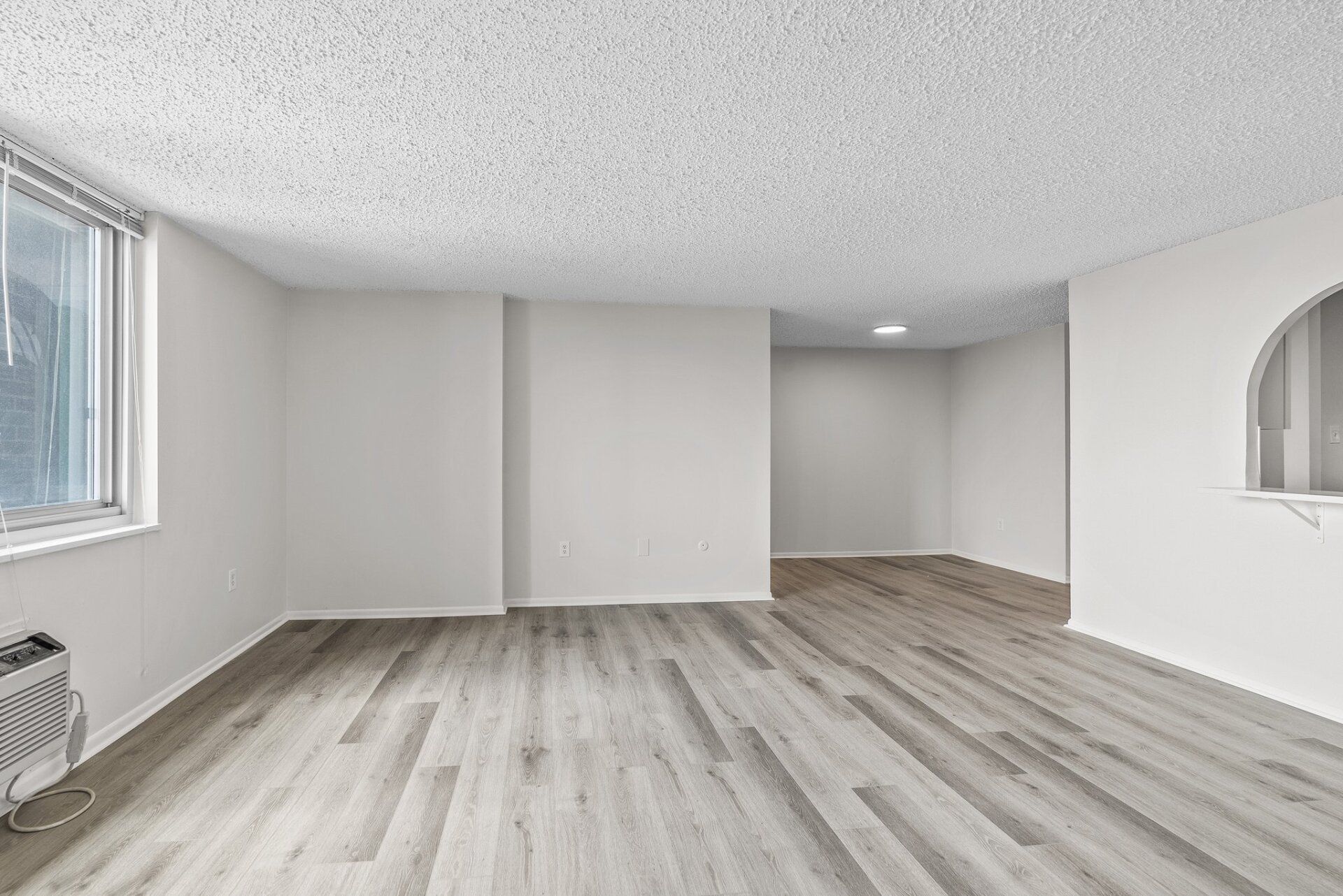 An empty living room with hardwood floors and white walls.