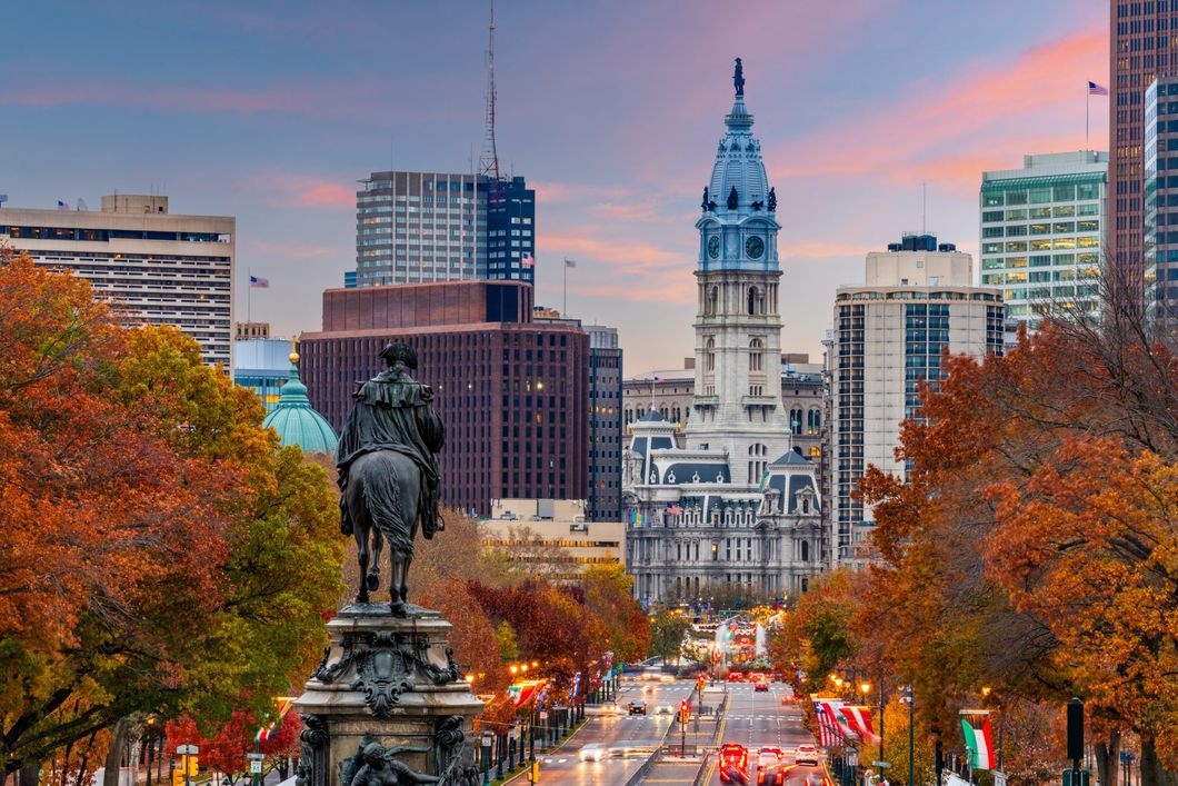 A statue of a man riding a horse in front of a city skyline.