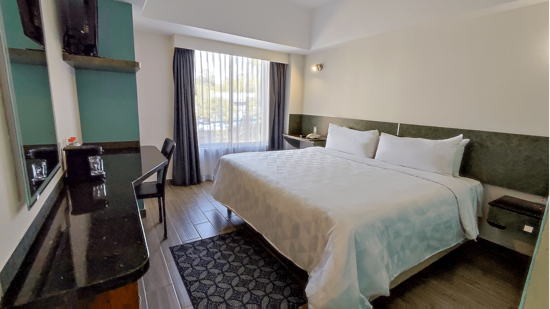 A hotel room with a king size bed and a desk.