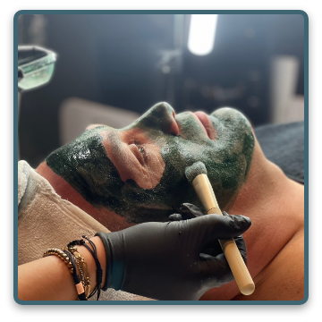 Eine Frau bekommt eine grüne Maske aufs Gesicht