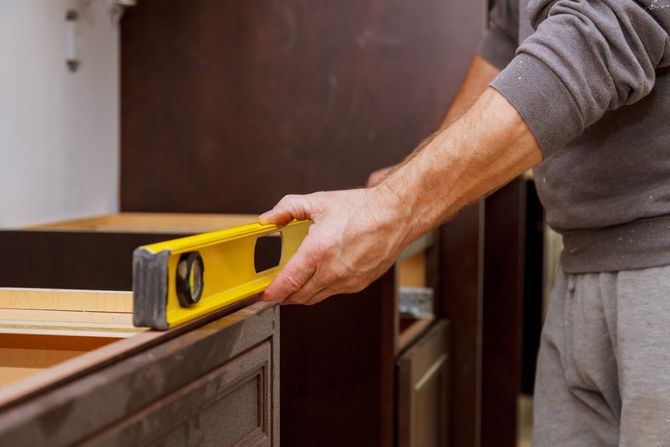 Person using a yellow level to measure a wooden cabinet during home installation