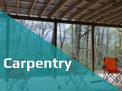 An outdoor wooden deck with chairs under a roof, overlooking a forest, partially obscured by a teal 