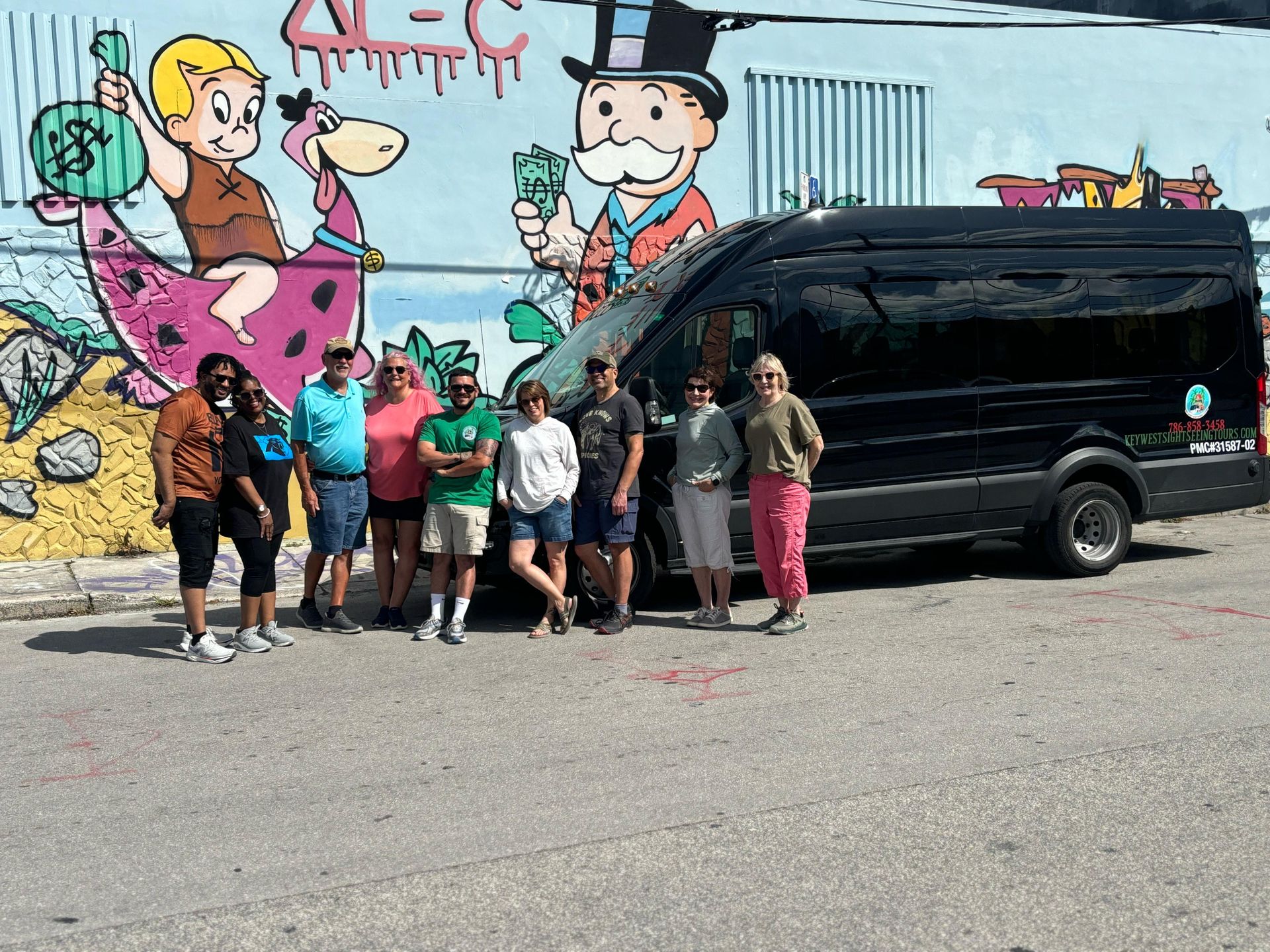 Tour guide taking a group photo of passengers in front of a colorful mural at Wynwood Walls Miami.