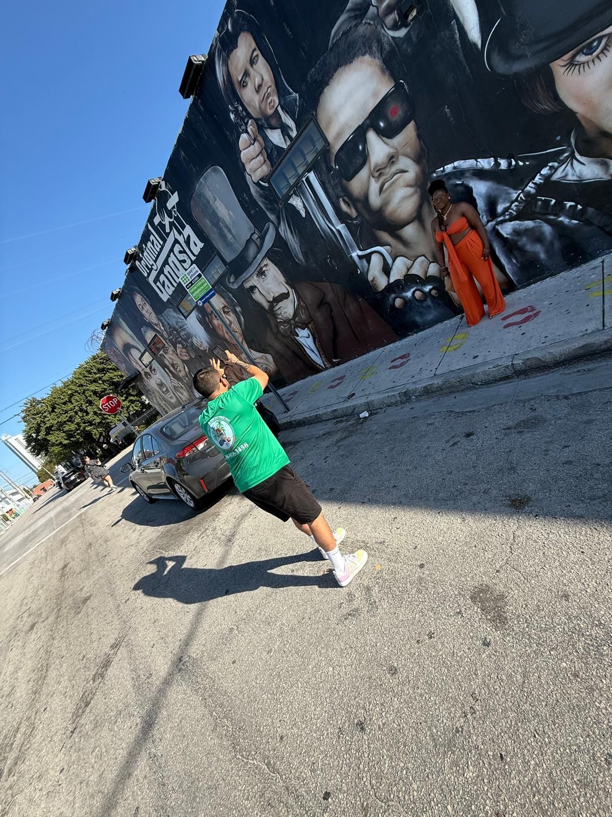 Tour guide taking a photo of passengers in front of a colorful mural at Wynwood Walls, capturing the vibrant street art experience.