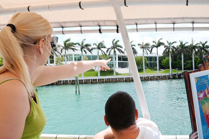 Guests on a Miami celebrity homes boat tour pointing at a mansion on Star Island during a Miami sightseeing cruise
