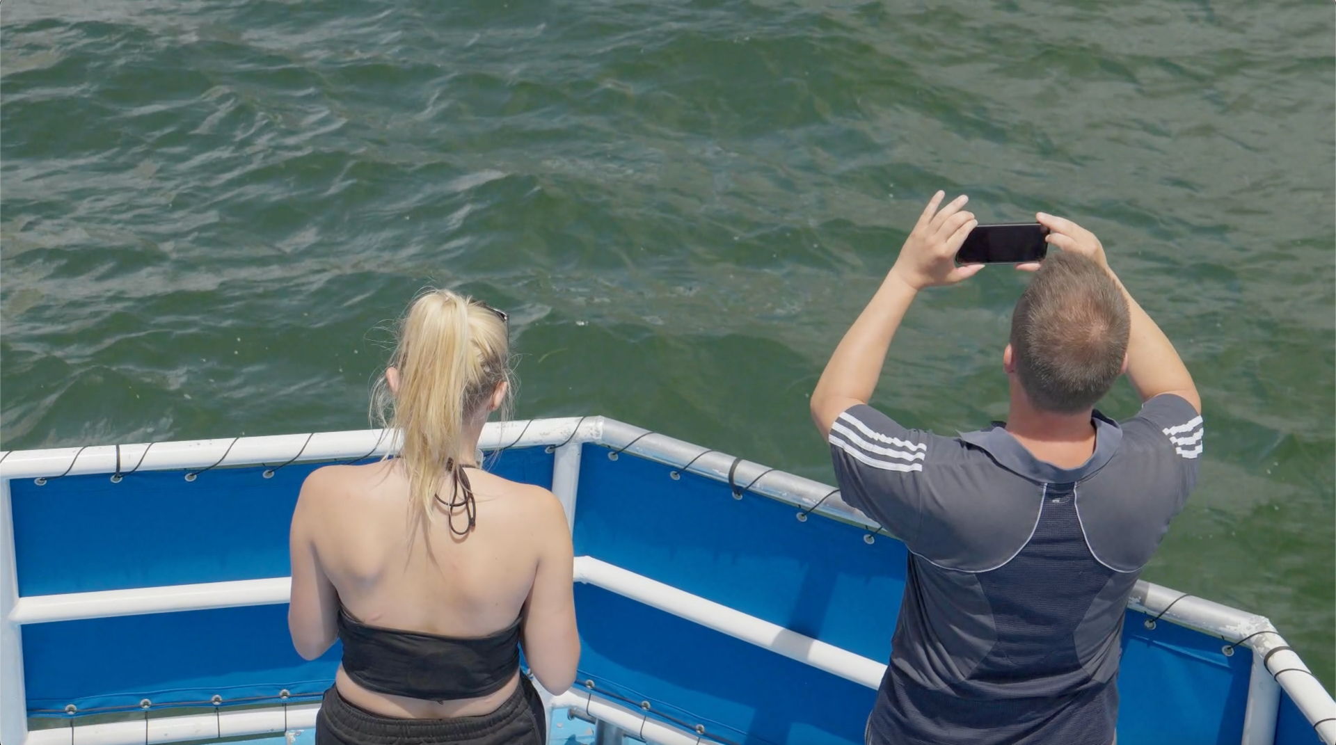 Man using his phone to take pictures while standing at the front of the vessel on a Miami boat tour