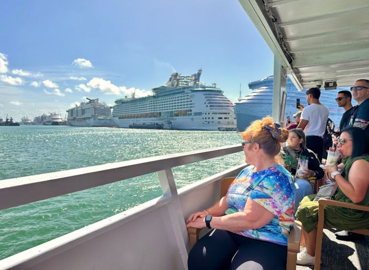 Cruise passengers enjoying scenic views of PortMiami from a sightseeing boat with mojitos in hand during a waterfront experience near Bayside