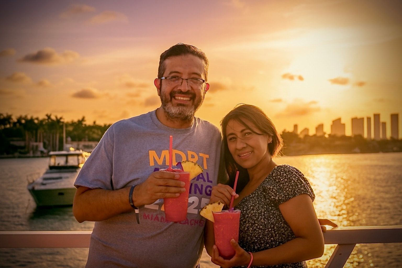 Couple enjoying drinks on a Miami sunset cruise with the glowing skyline at golden hour.