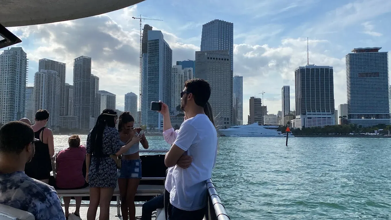 Visitors photographing the Biscayne Bay skyline with Downtown Miami, InterContinental Miami, Miami Tower, and waterfront skyscrapers in the background.