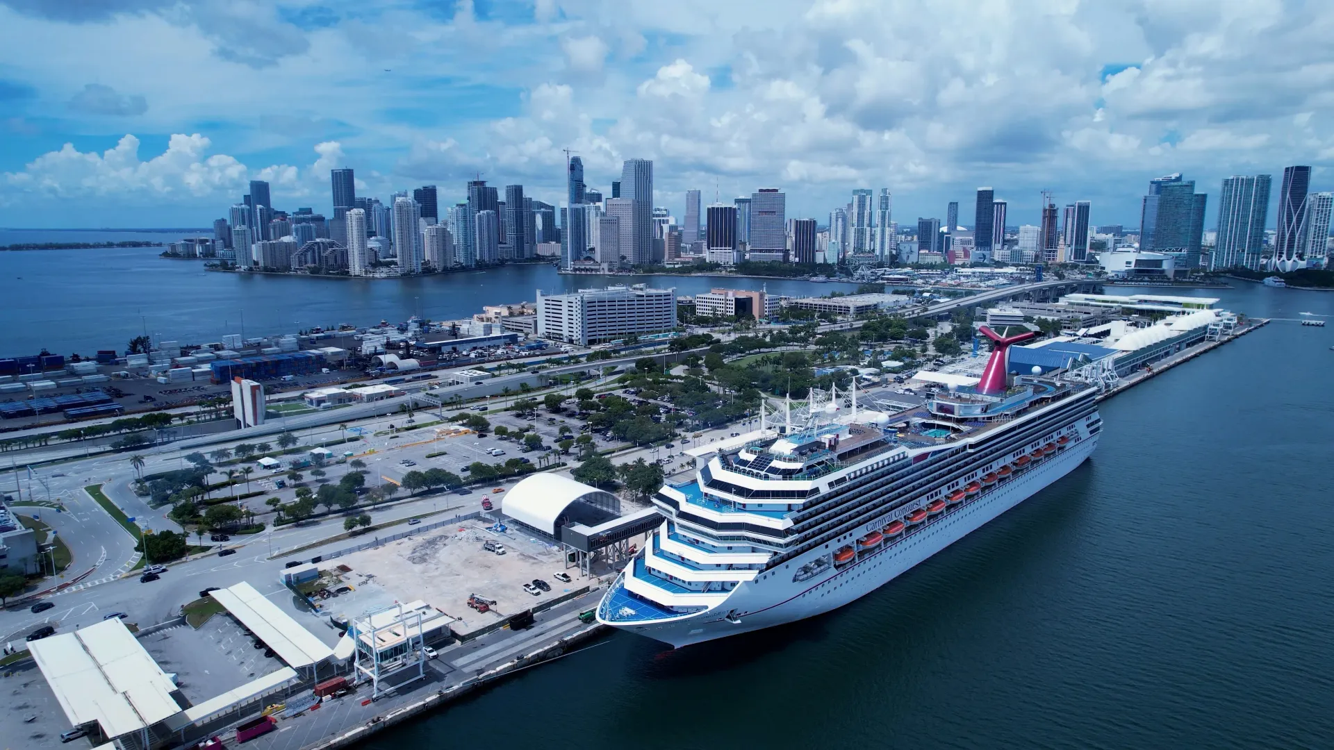 Cruise ship docked at the Port of Miami with downtown Miami skyline and Biscayne Bay in the background.