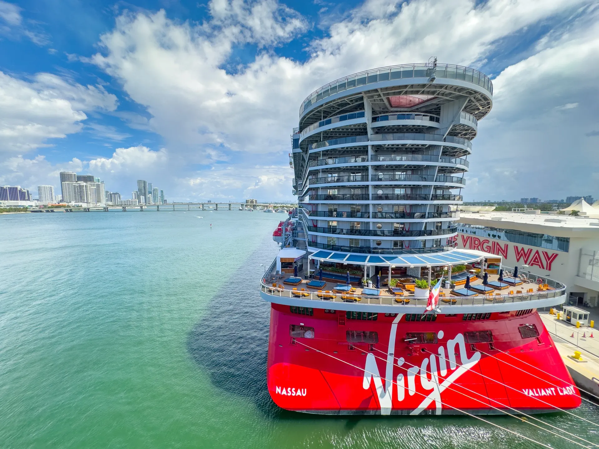 Cruise ship docked at the Port of Miami with downtown Miami skyline in the background before departure.